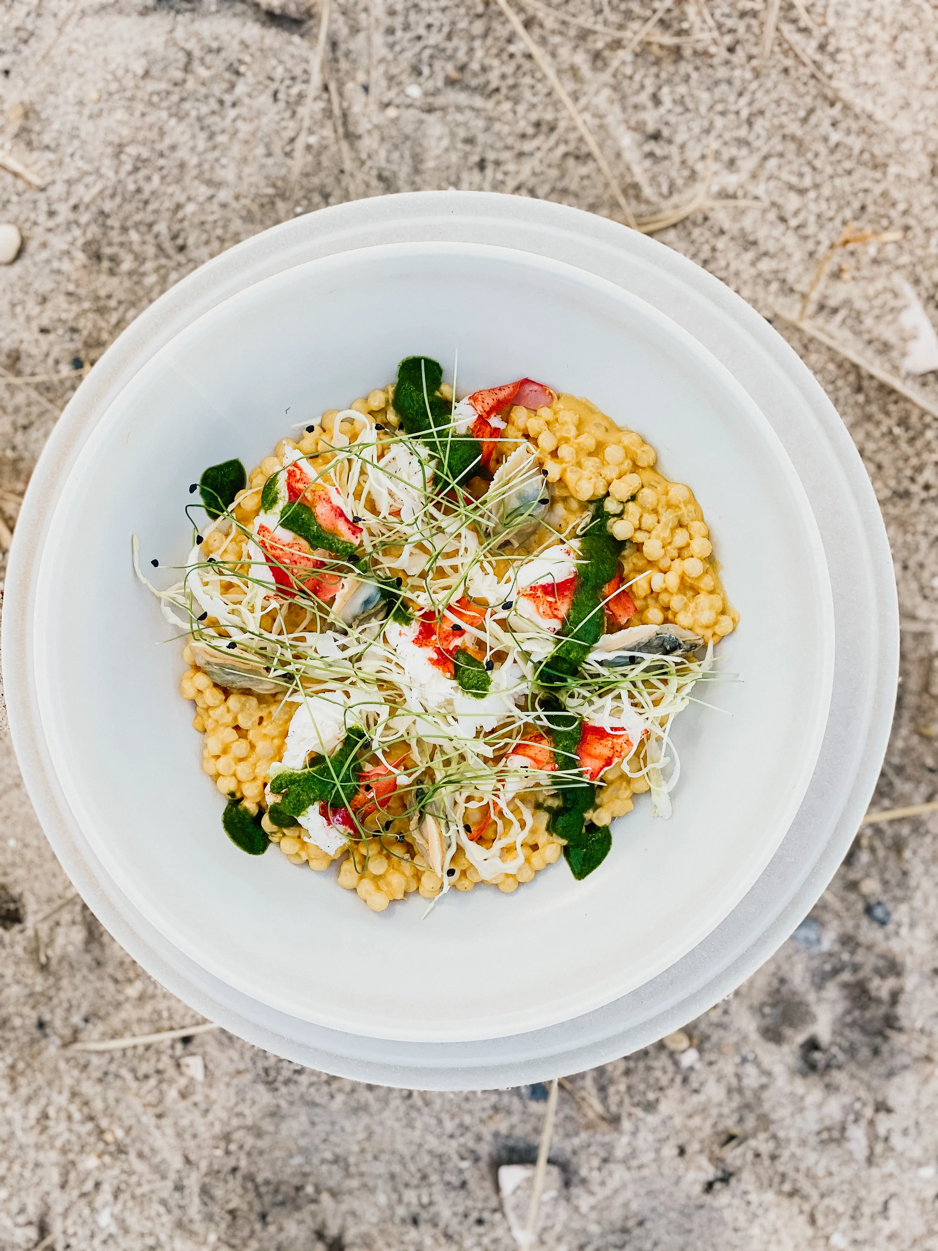 Round bowl seafood dish presented over sand
